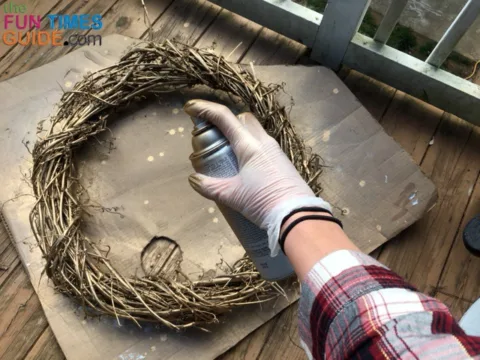 Painting this large grapevine wreath with gold spray paint.